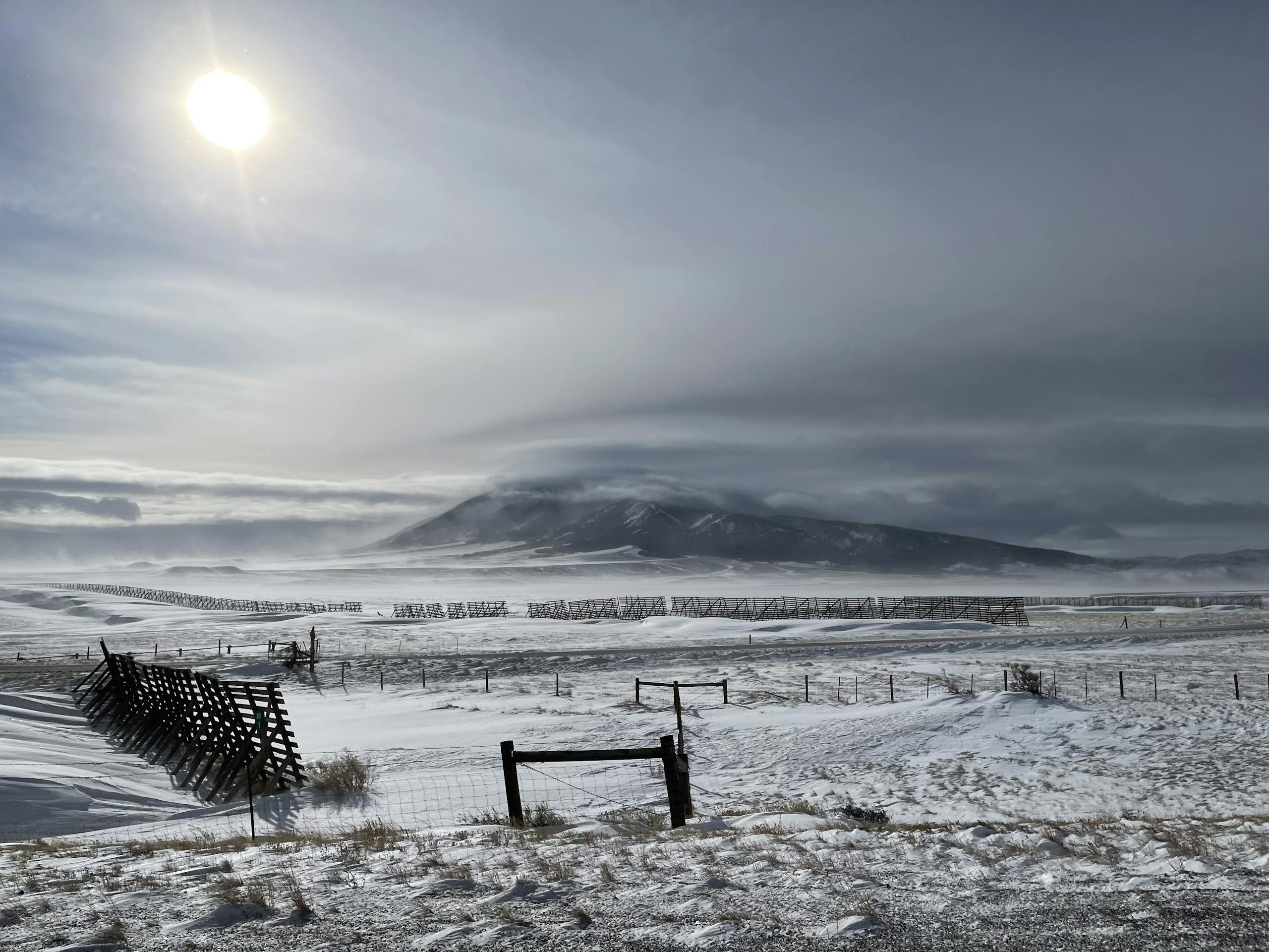 Sun shining over a snow-covered field and mountain in Wyoming, USA.